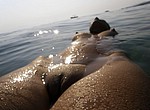 Tanned woman with hard nipples and sweet shaved pussy swimming in the ocean and flashing her goods from underwater